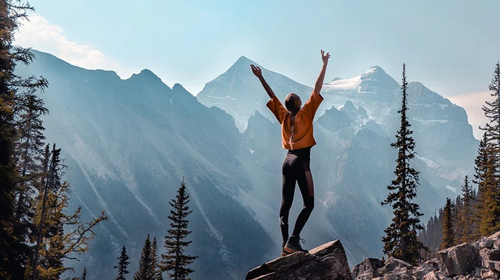 woman standing on a peak with hands raised