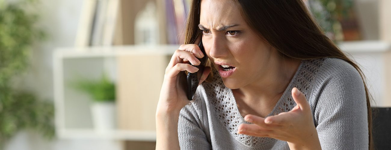 Angry Woman Calling Arguing On Smart Phone Sitting In The Living